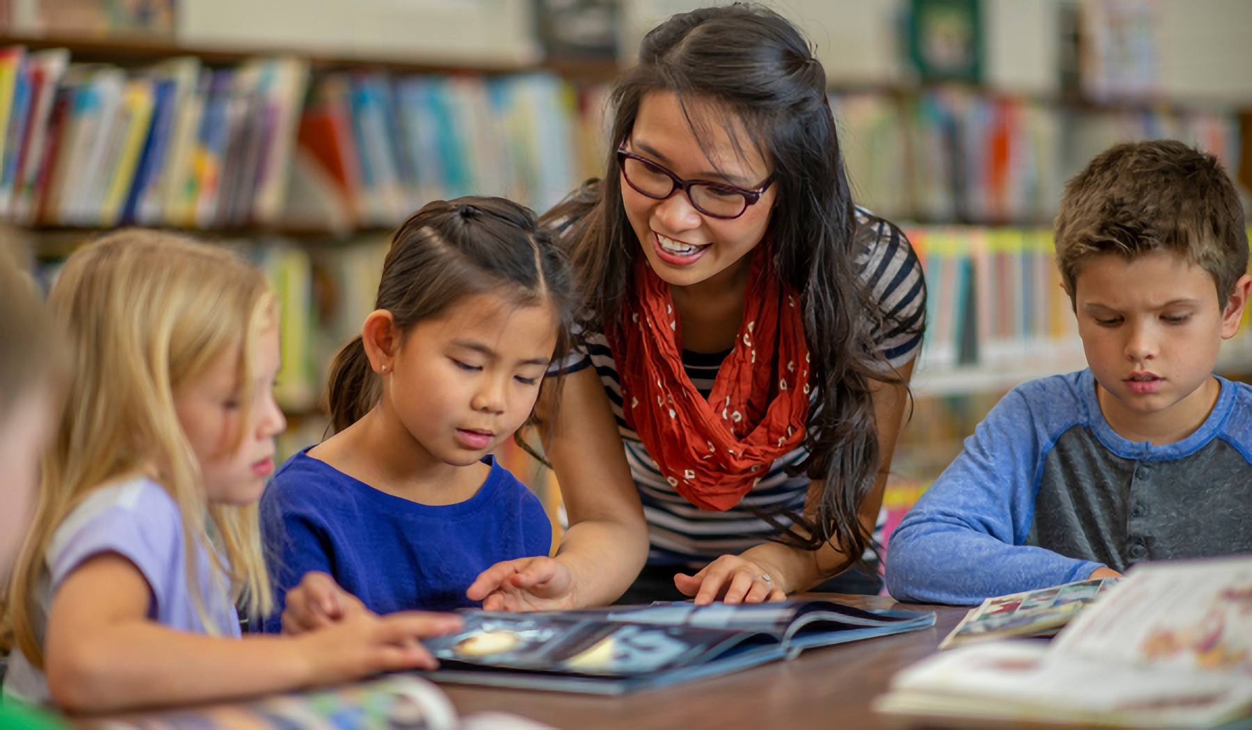 Students reading and learning in the library with their teacher